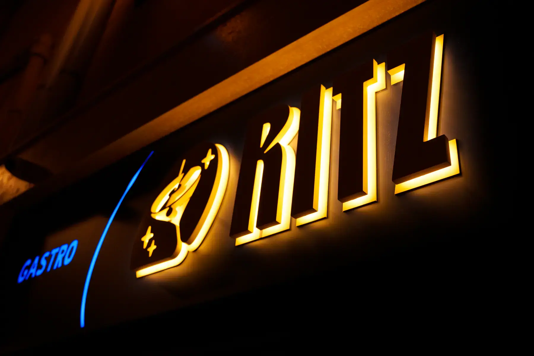The backlit Ritz logo on the gastropub facade at night