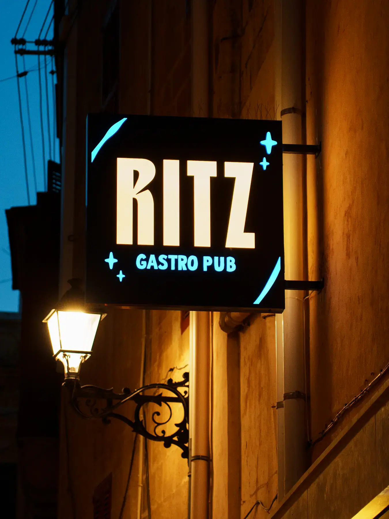 The Ritz Gastro Pub hanging sign beside a wall lamp