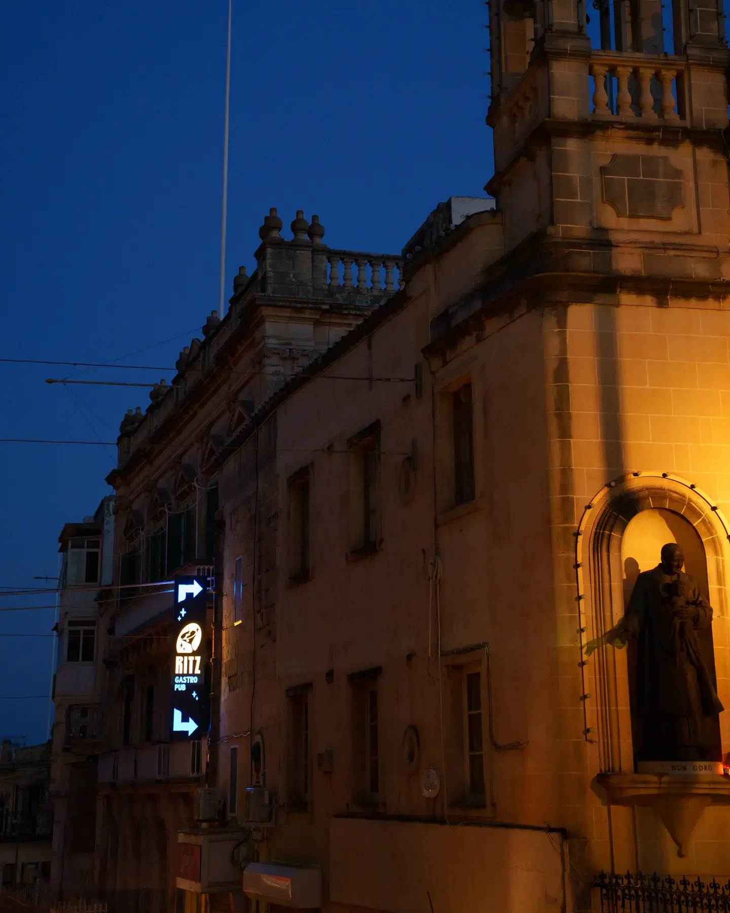 A historic Victoria street at dusk, with the Ritz sign glowing below