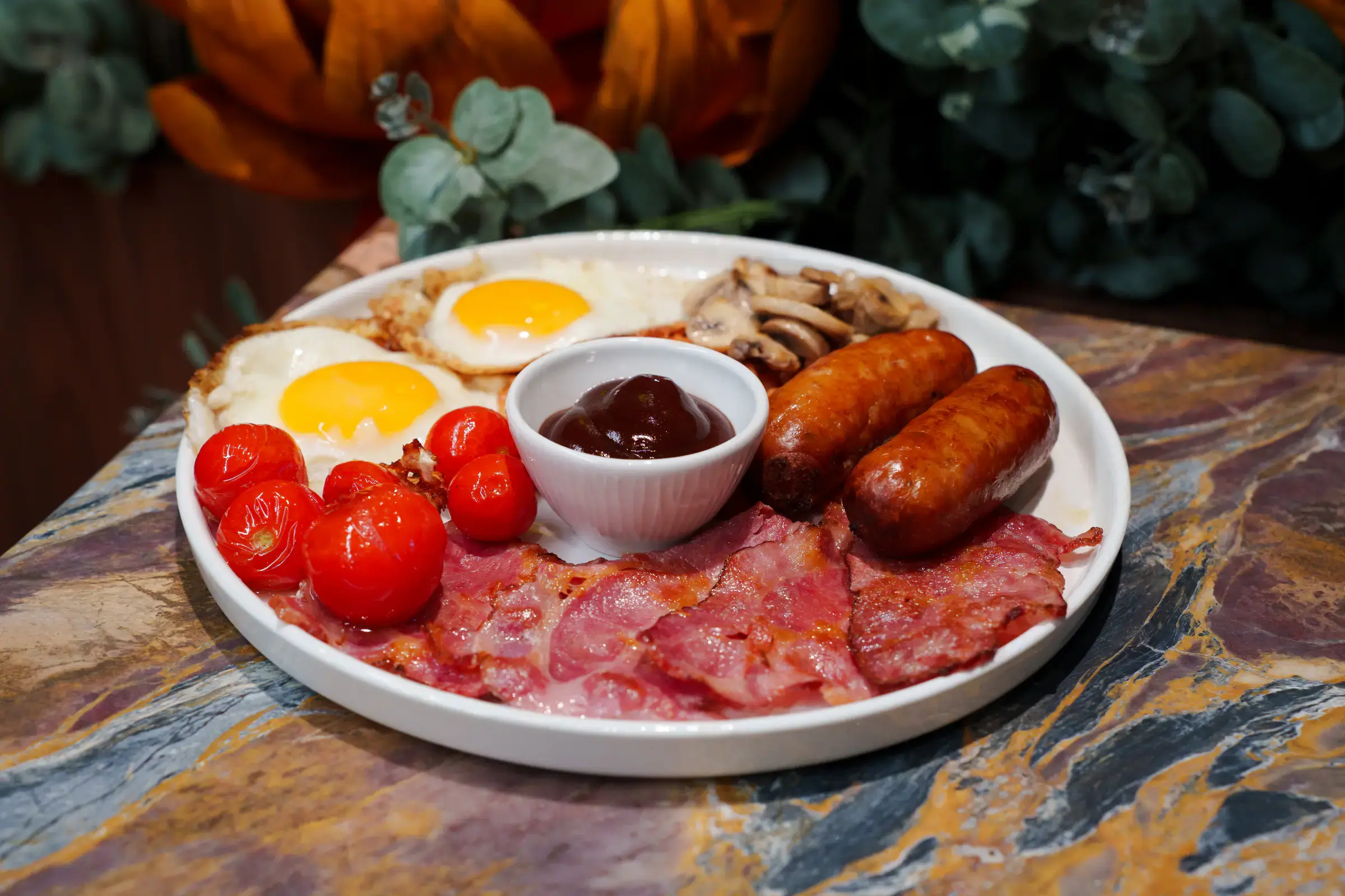 Full English breakfast with fried eggs, sausages, bacon, cherry tomatoes and beans