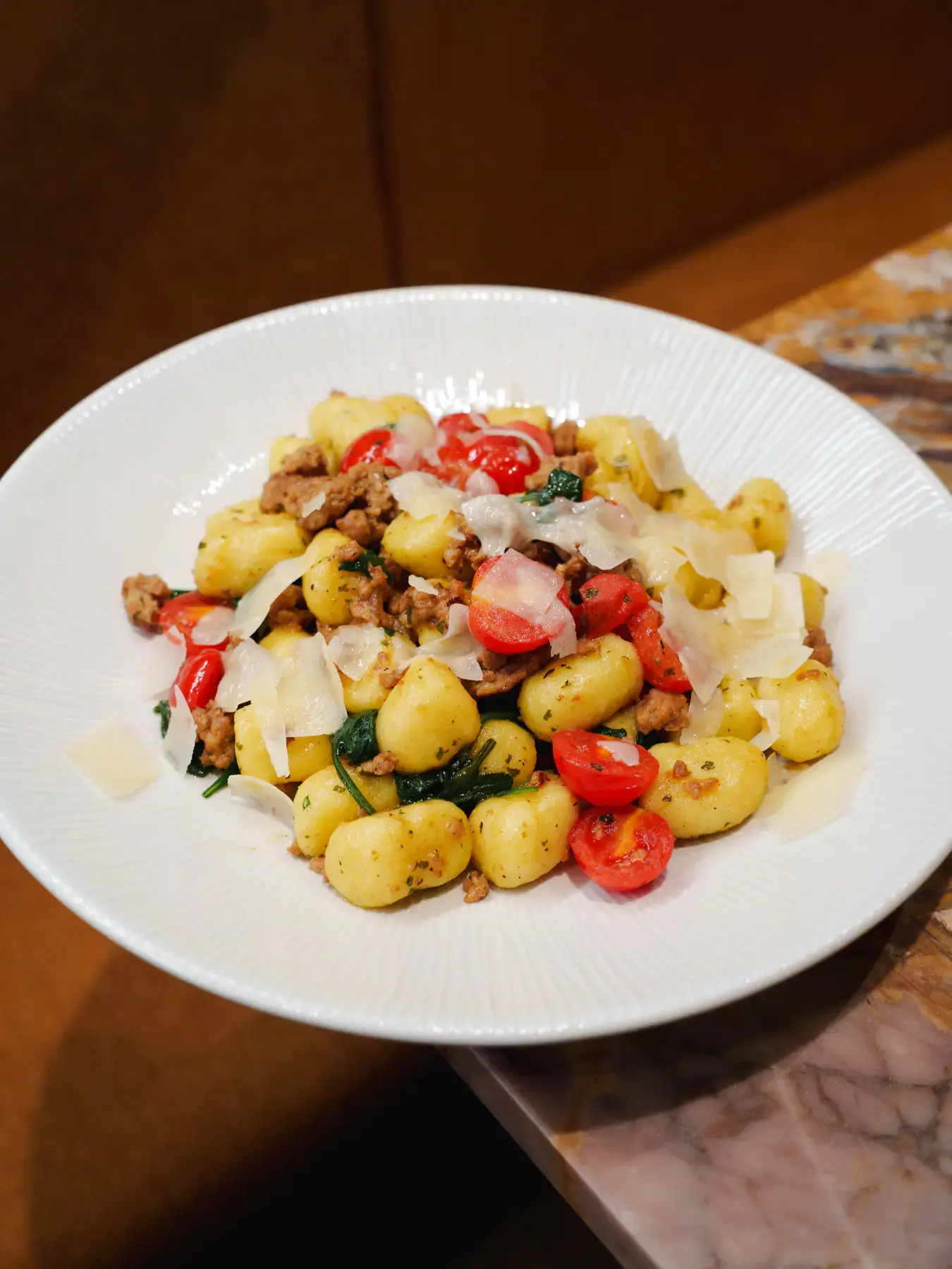Potato gnocchi with crumbled sausage, spinach and cherry tomatoes