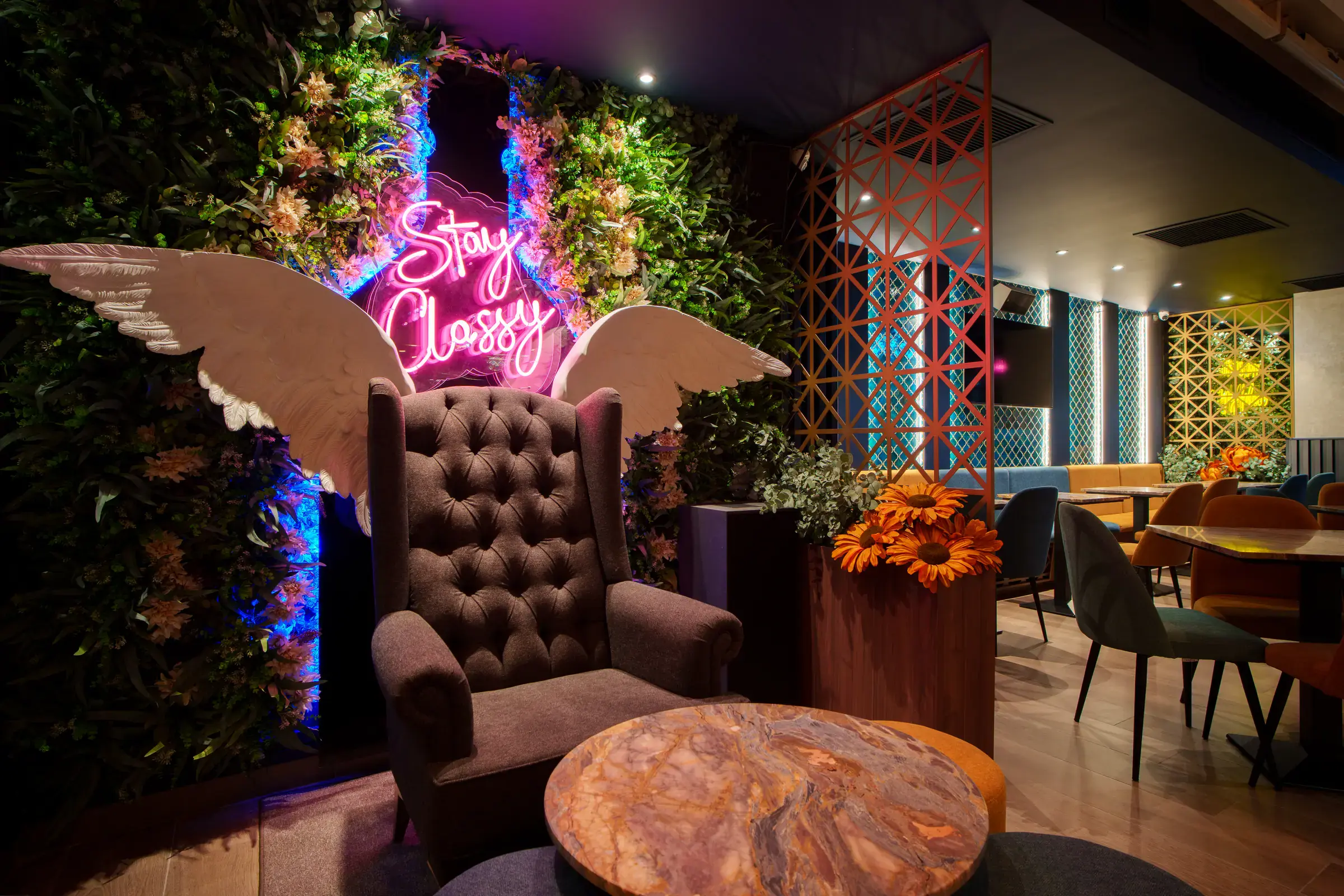 A winged armchair beneath the Stay Classy neon
